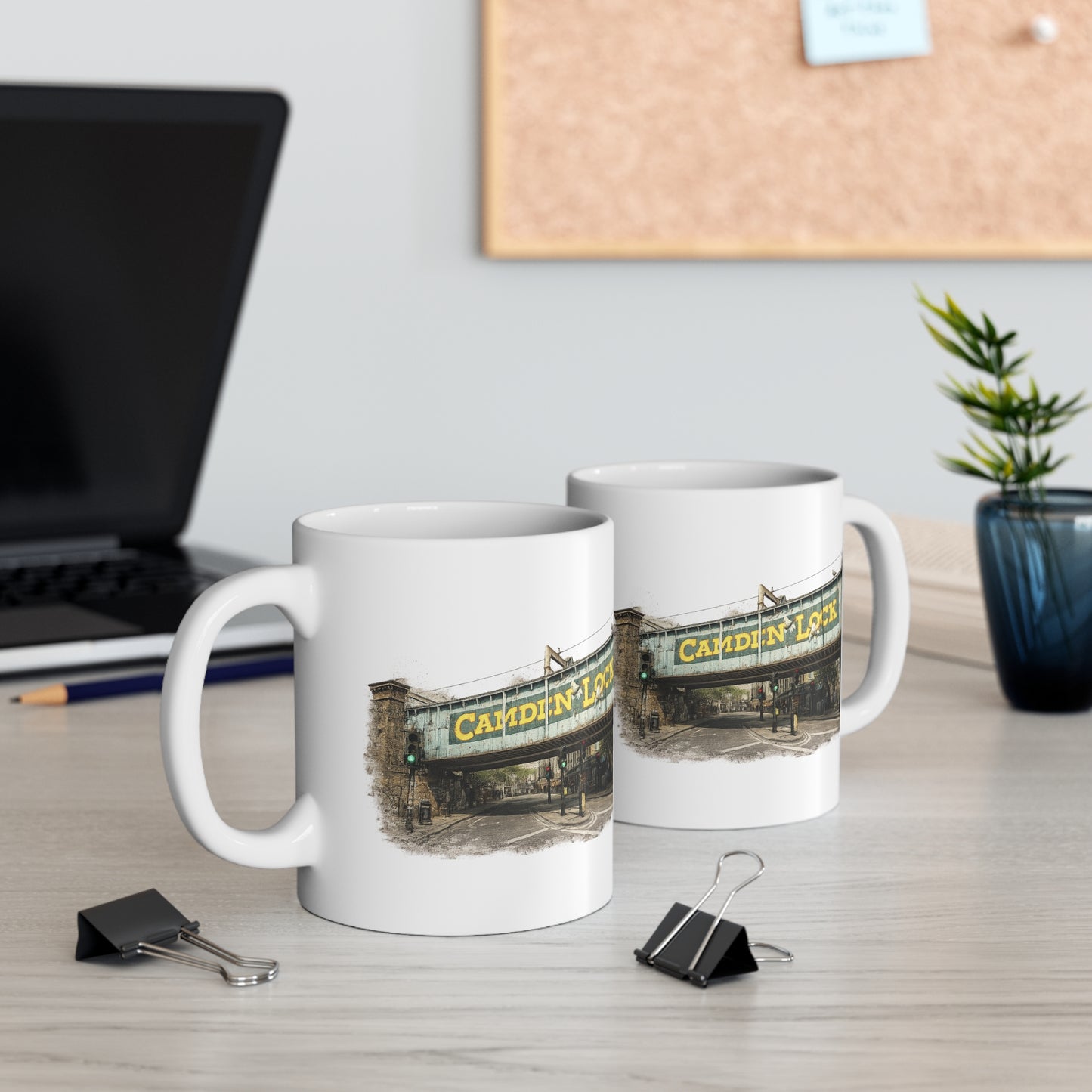 Two mugs with a Camden Lock design on a desk with office supplies and a plant.
