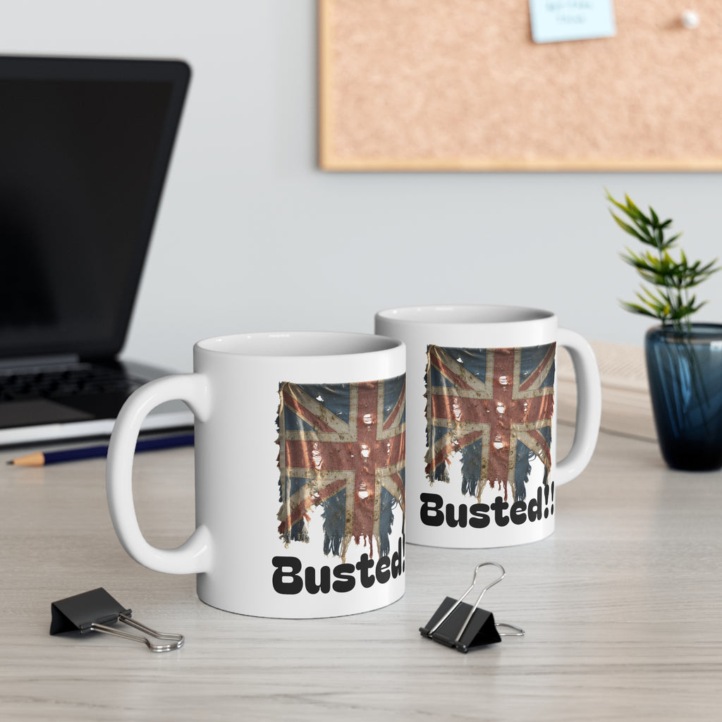Two mugs with British flag design and 'Busted!' text on a desk with office items.