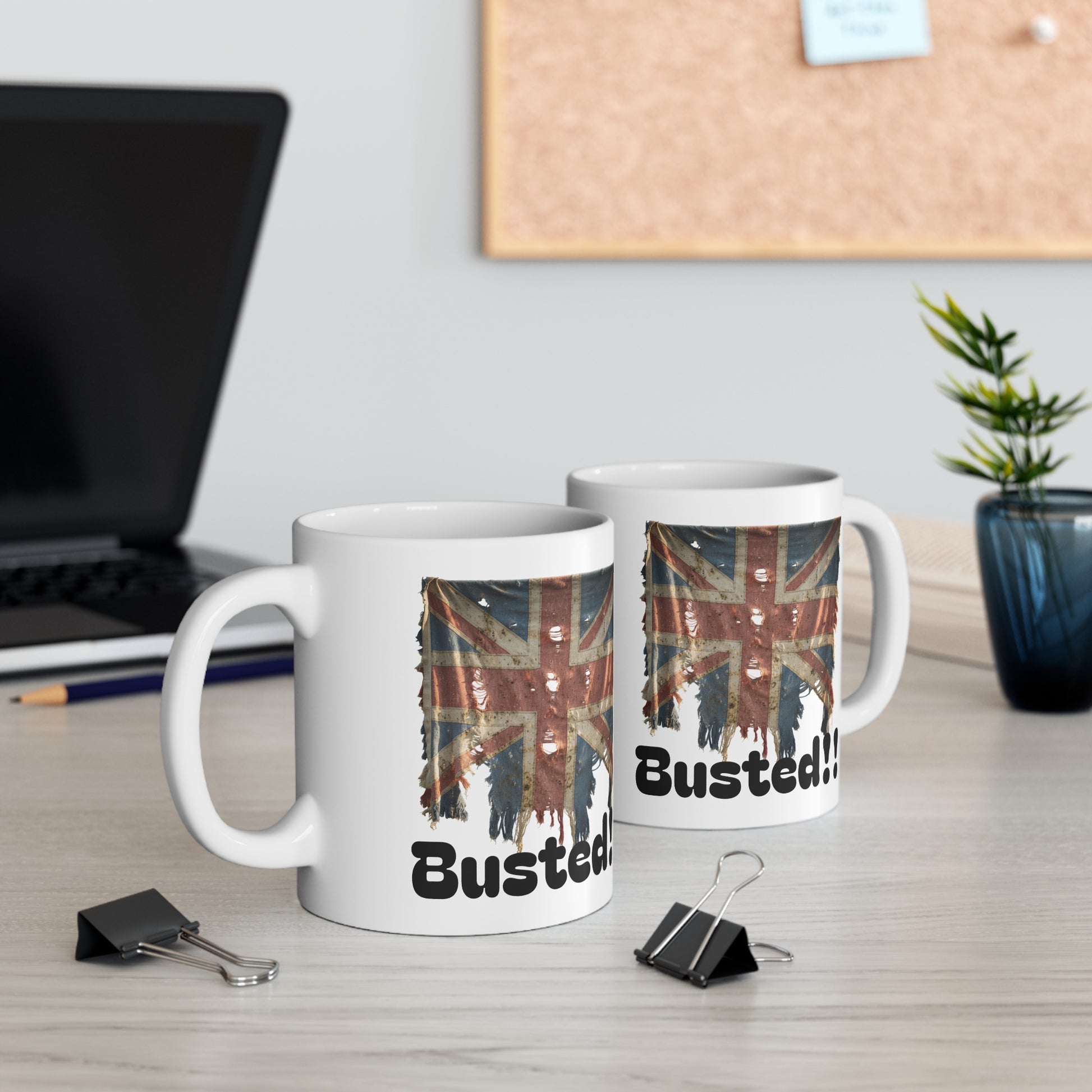 Two mugs with British flag design and 'Busted!' text on a desk with office items.