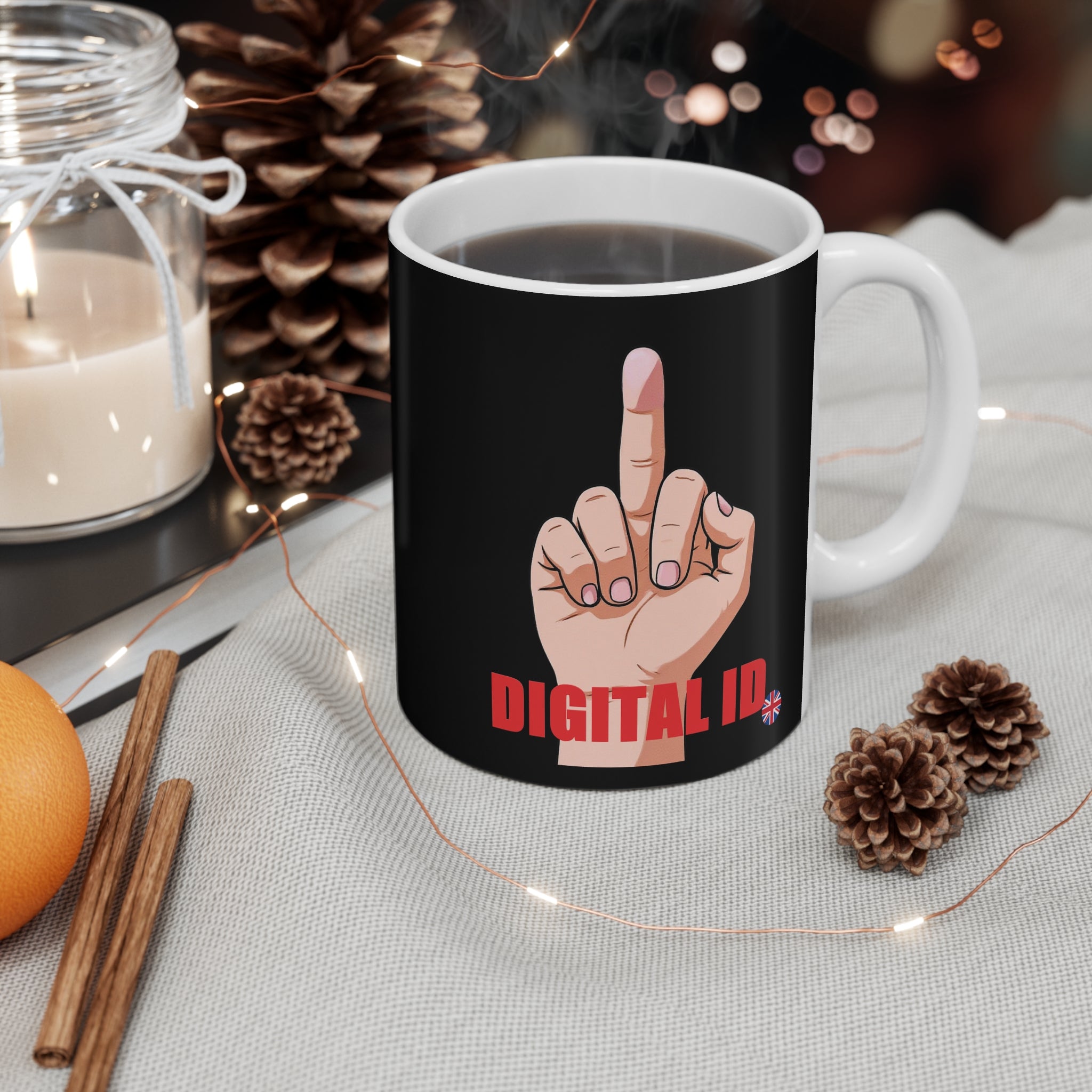 Black mug with a hand gesture design and 'DIGITAL ID' text, placed on a table with decorative items.