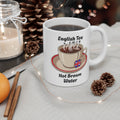 White mug with 'English Tea Hot Brown Water' text and tea cup illustration on a table with decorative items.