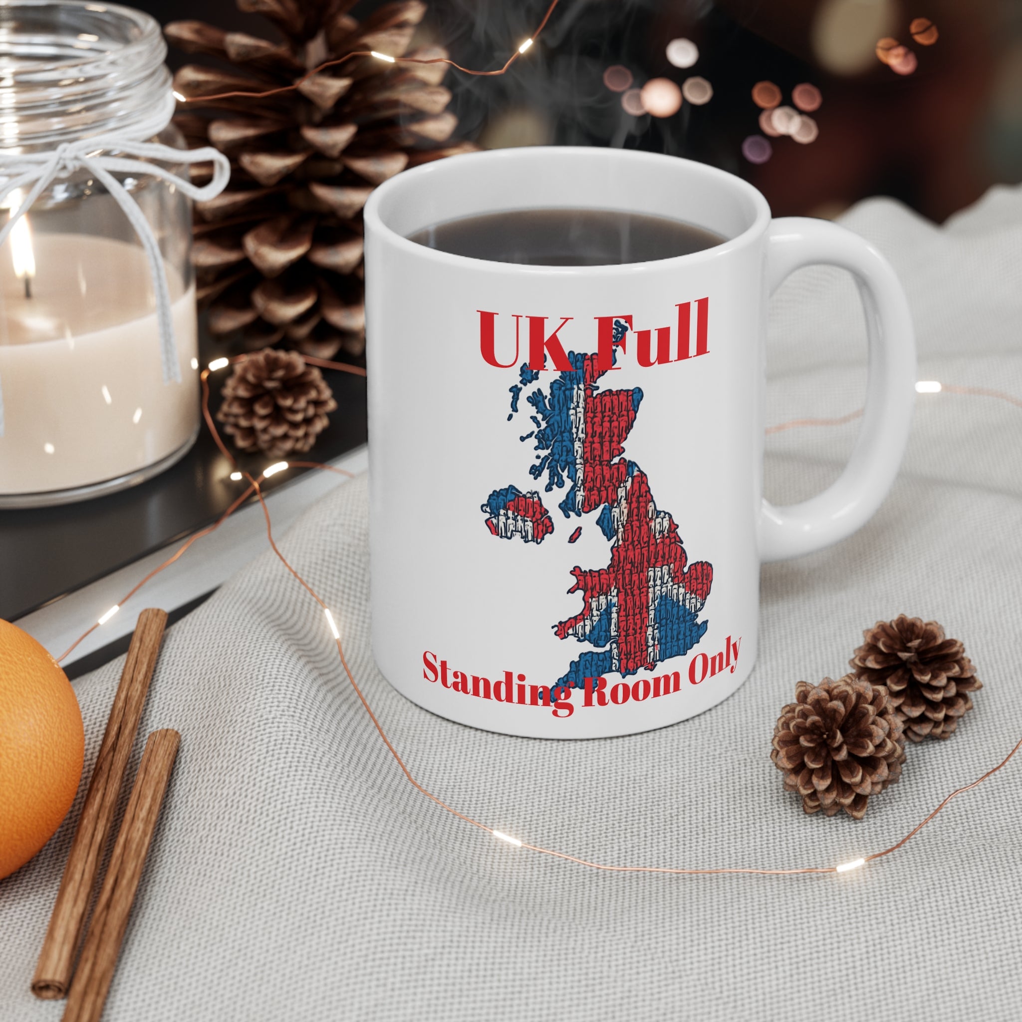 White mug with UK map design  and text, UK full standing room only surrounded by decorative items on a table.