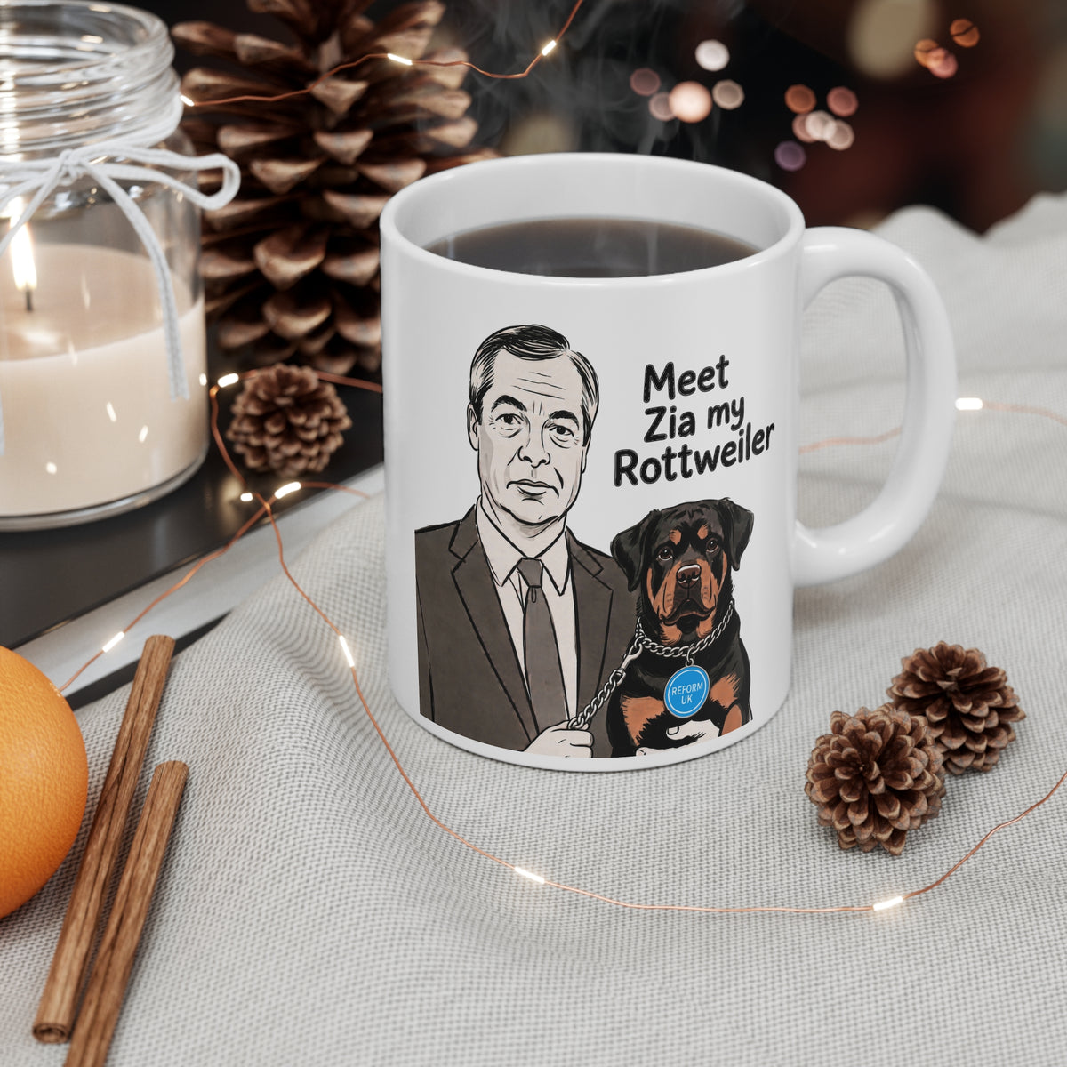 A white ceramic mug with a printed illustration of a man and a Rottweiler dog with the text 'Meet Zia my Rottweiler', shown on a table with a candle, pinecones, cinnamon sticks, and fairy lights.