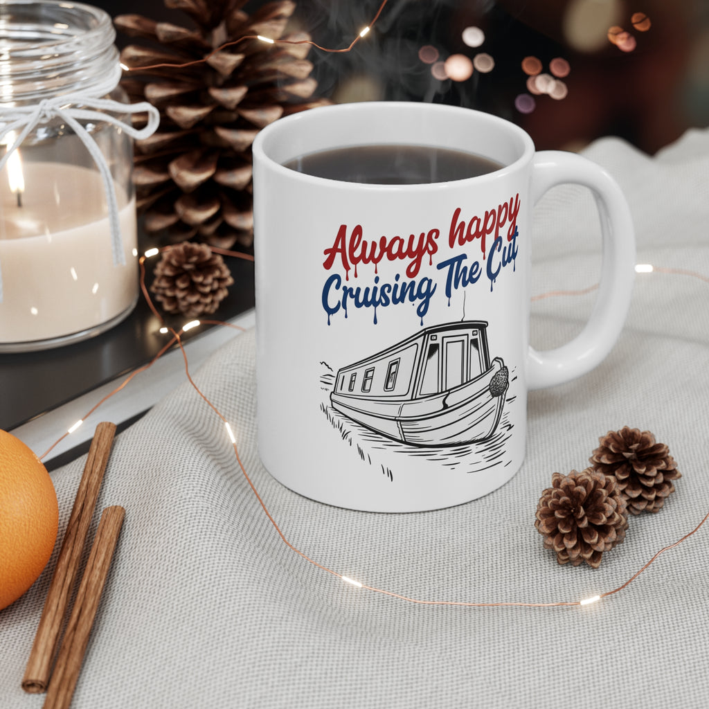 White mug with 'Always happy Cruising The Cut' text and boat illustration, surrounded by decorative items on a table.