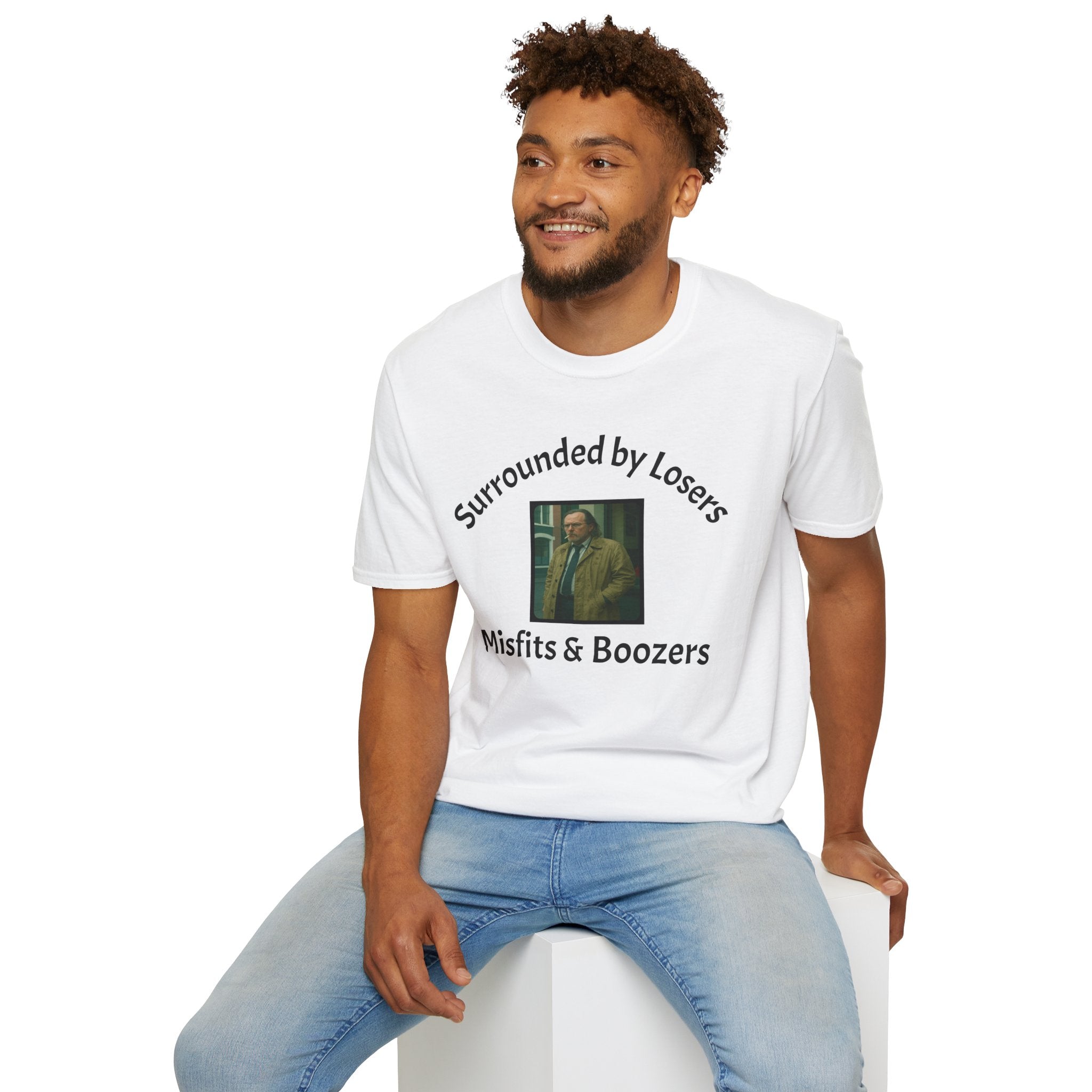A man sitting wearing a White T-Shirt features a bold design that reads 'slow horses surrounded by Losers, Misfits &amp; Boozers', from the slow horses t v show starring Gary Oldman giving off a rebellious and edgy vibe. 