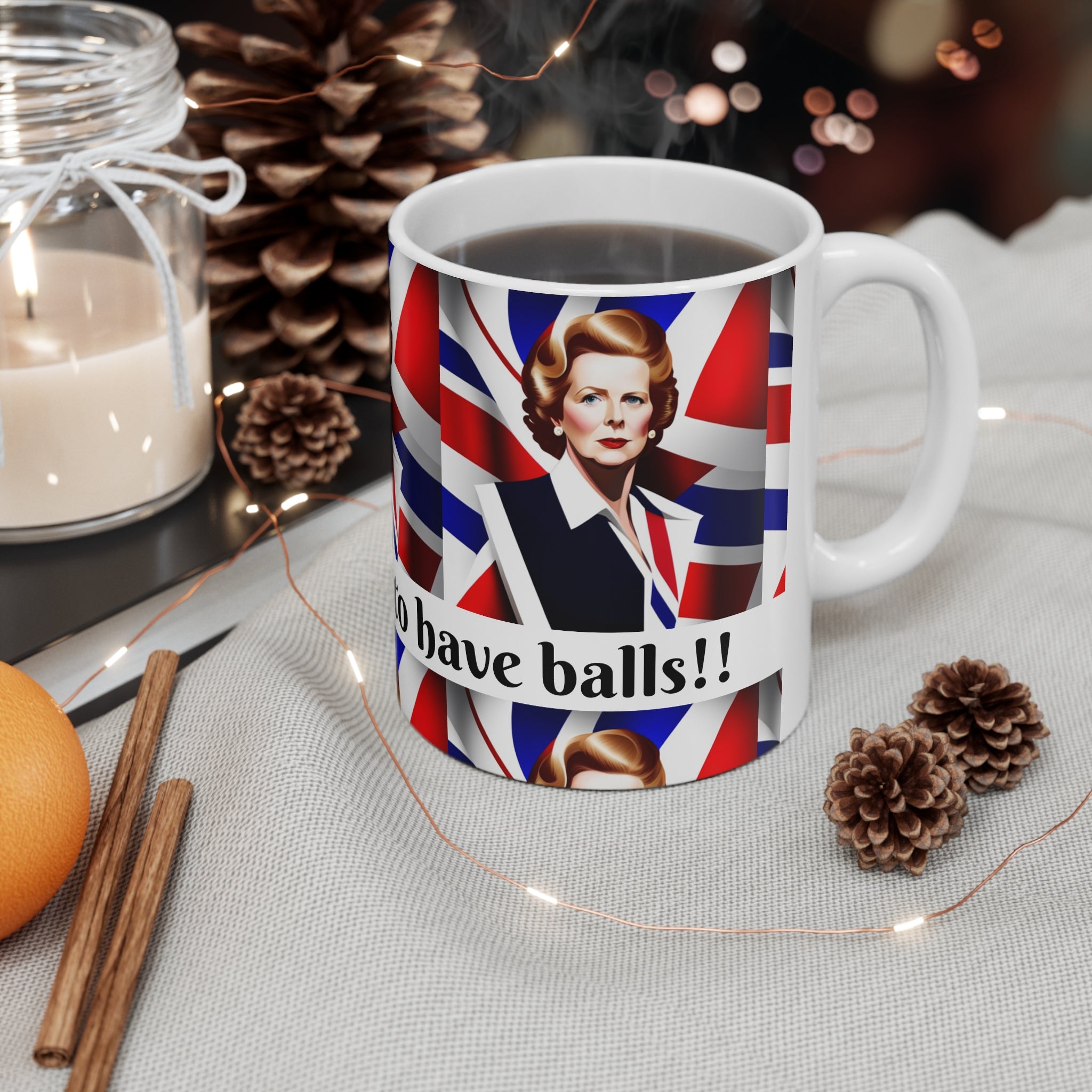 Mug with a Union Jack design featuring a Margaret Thatcher portrait and text, placed on a decorative surface with candles and pine cones.