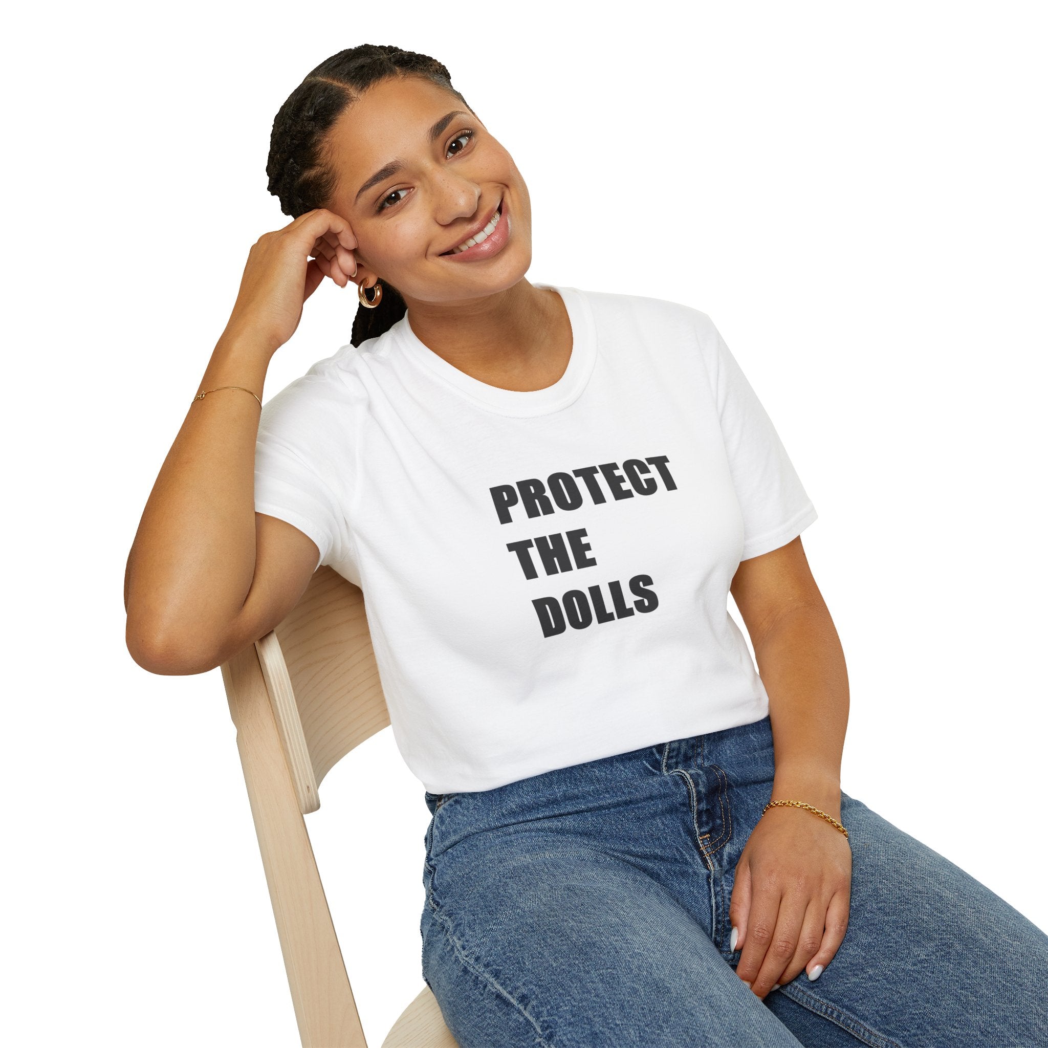 Person wearing a white t-shirt with 'PROTECT THE DOLLS' text, sitting on a chair.