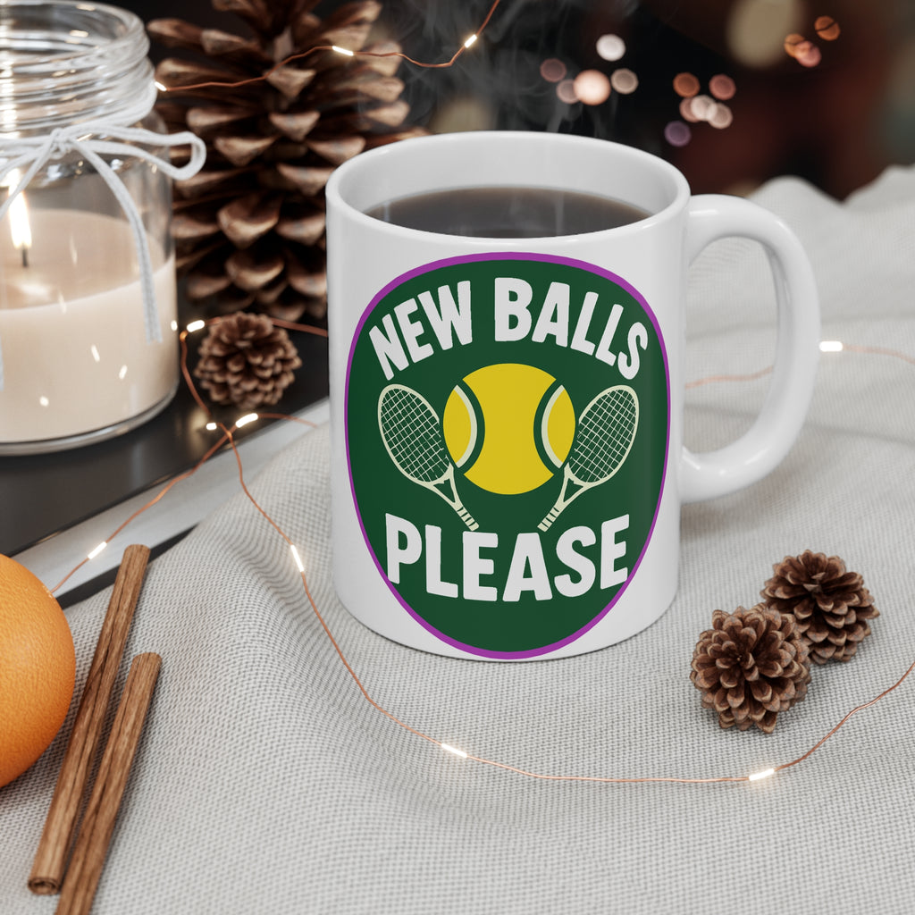 White mug with 'New Balls Please' design on a table with decorative items