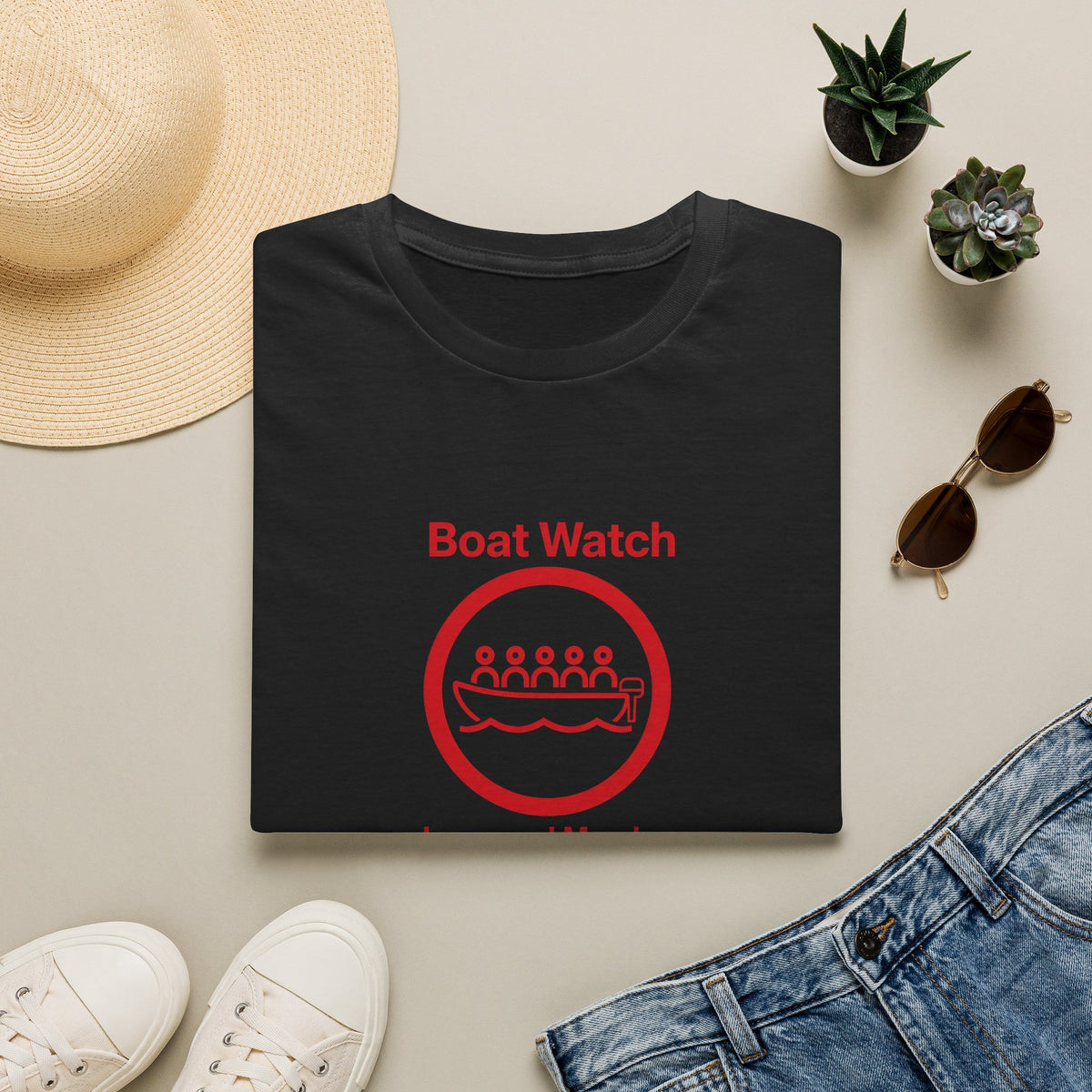 black t-shirt with 'boat watch graphic on a light surface with accessories.