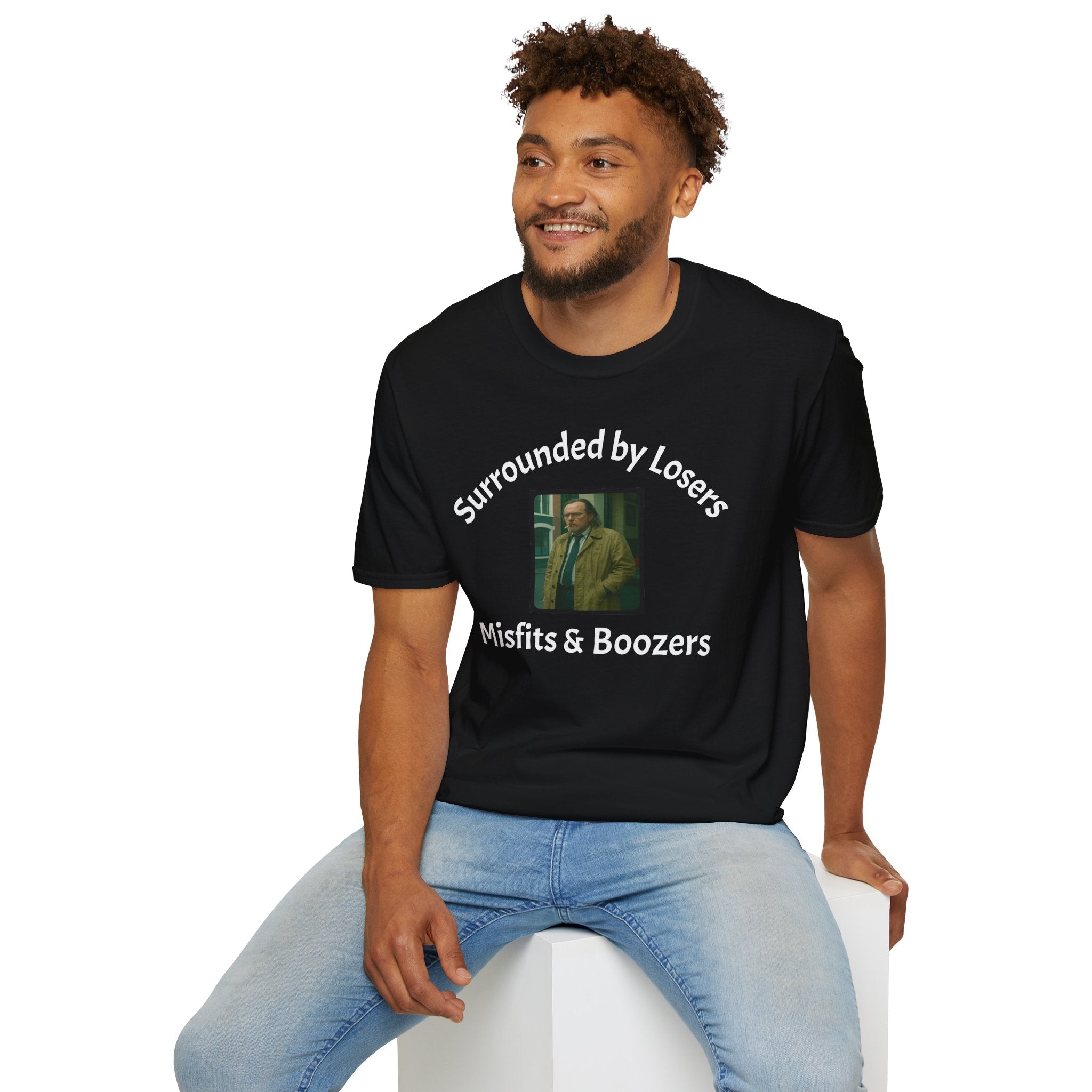 A man  sitting wearing a black T-Shirt features a bold design that reads 'slow horses surrounded by Losers, Misfits &amp; Boozers', from the slow horses t v show starring Gary Oldman giving off a rebellious and edgy vibe. 