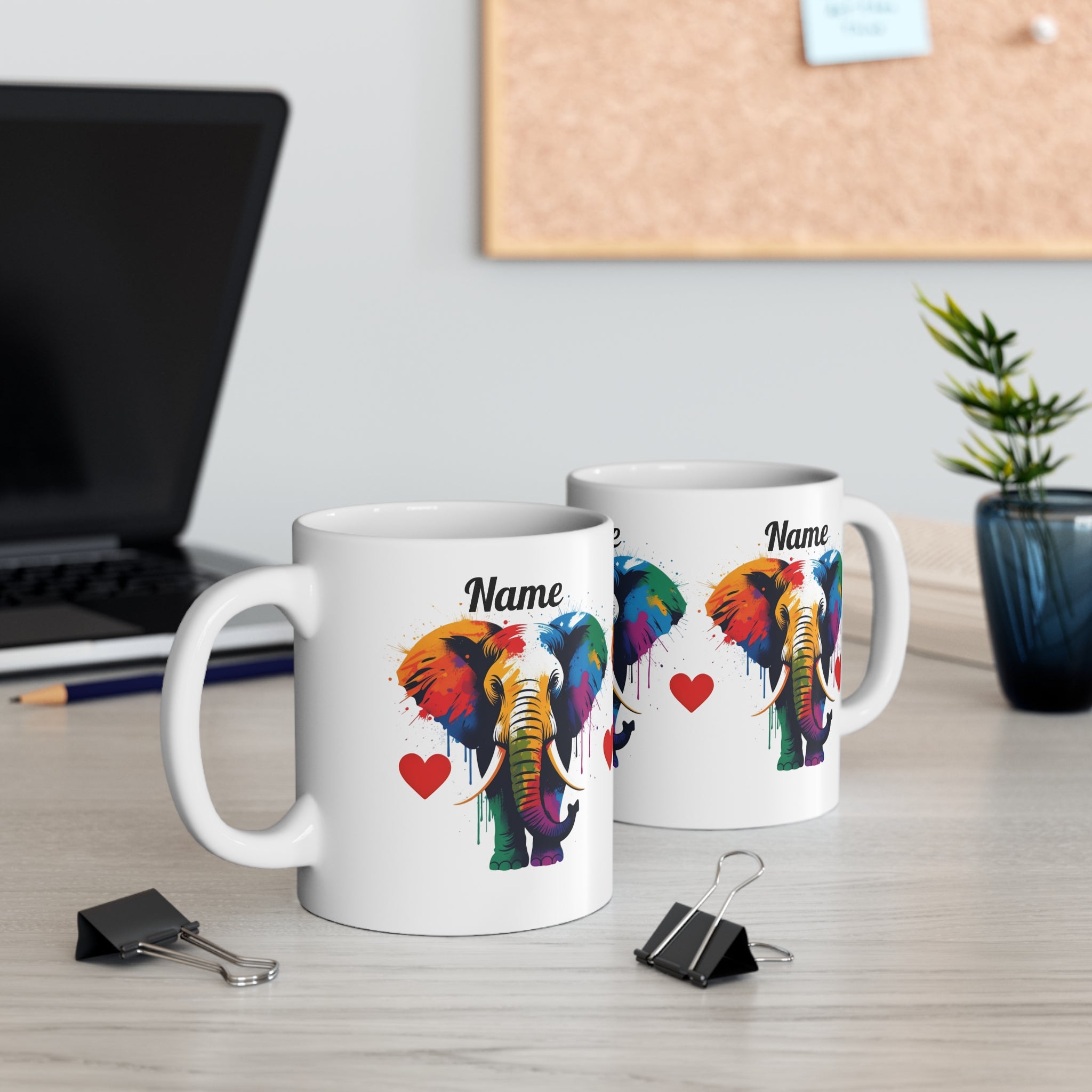 Two white mugs with colourful PERSONALISED elephant designs on a desk.