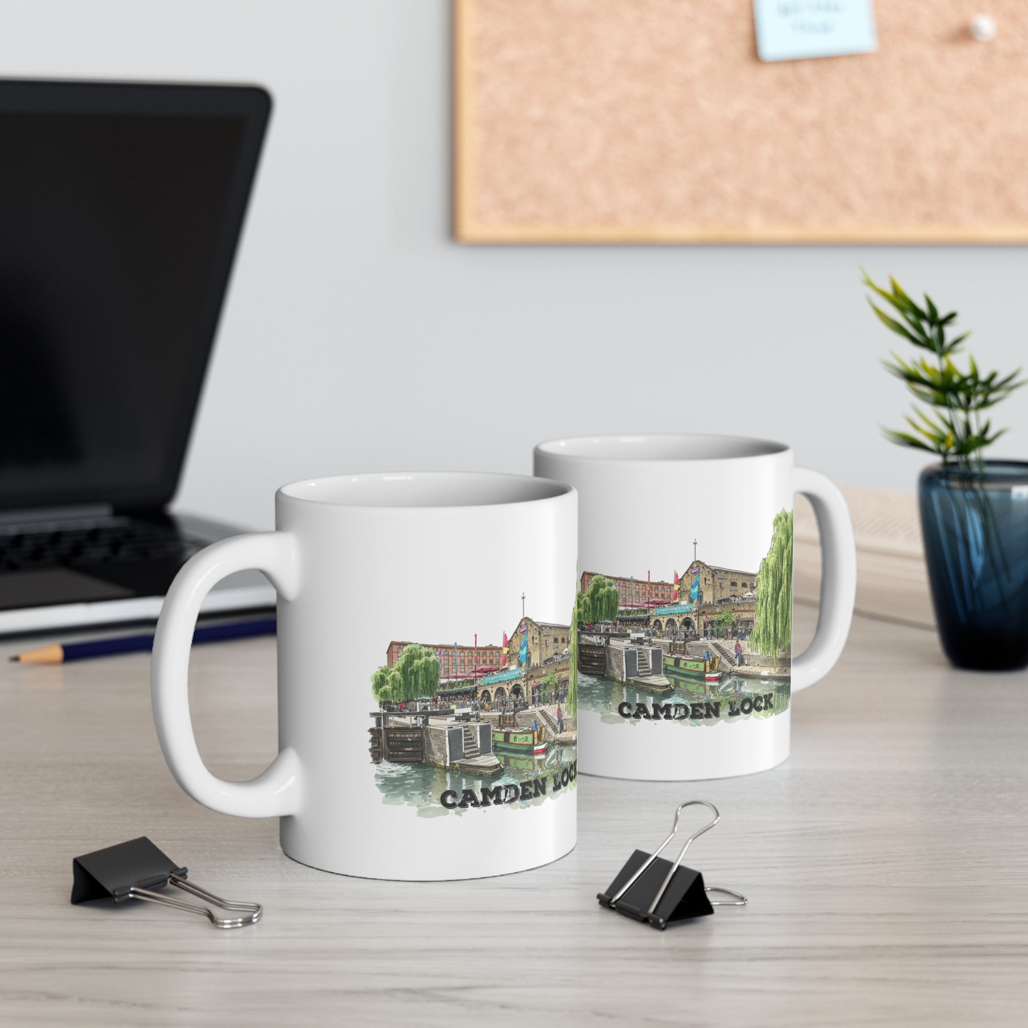 Two mugs with a Camden Lock design on a desk with office supplies and a plant.
