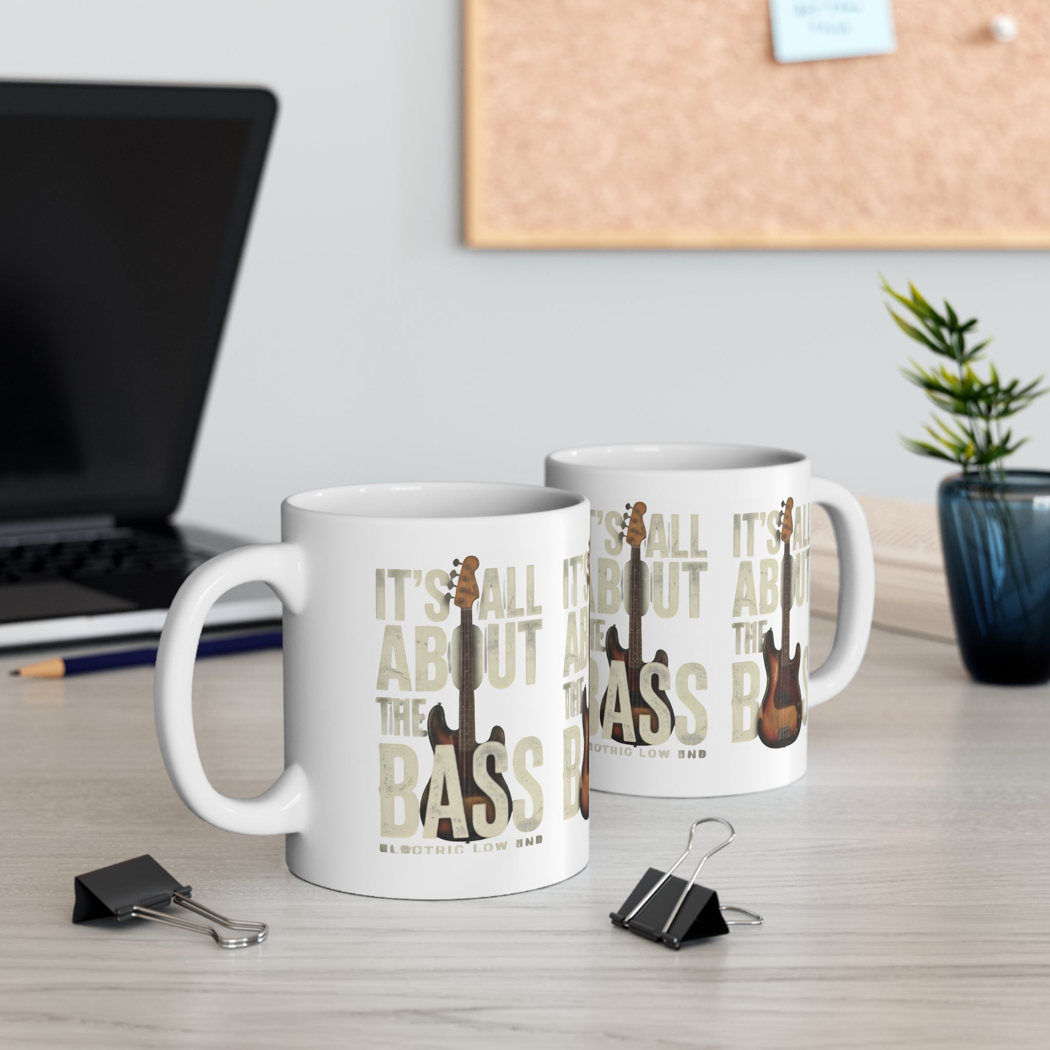 Two mugs with 'It's All About the Bass' design on a desk with office items.