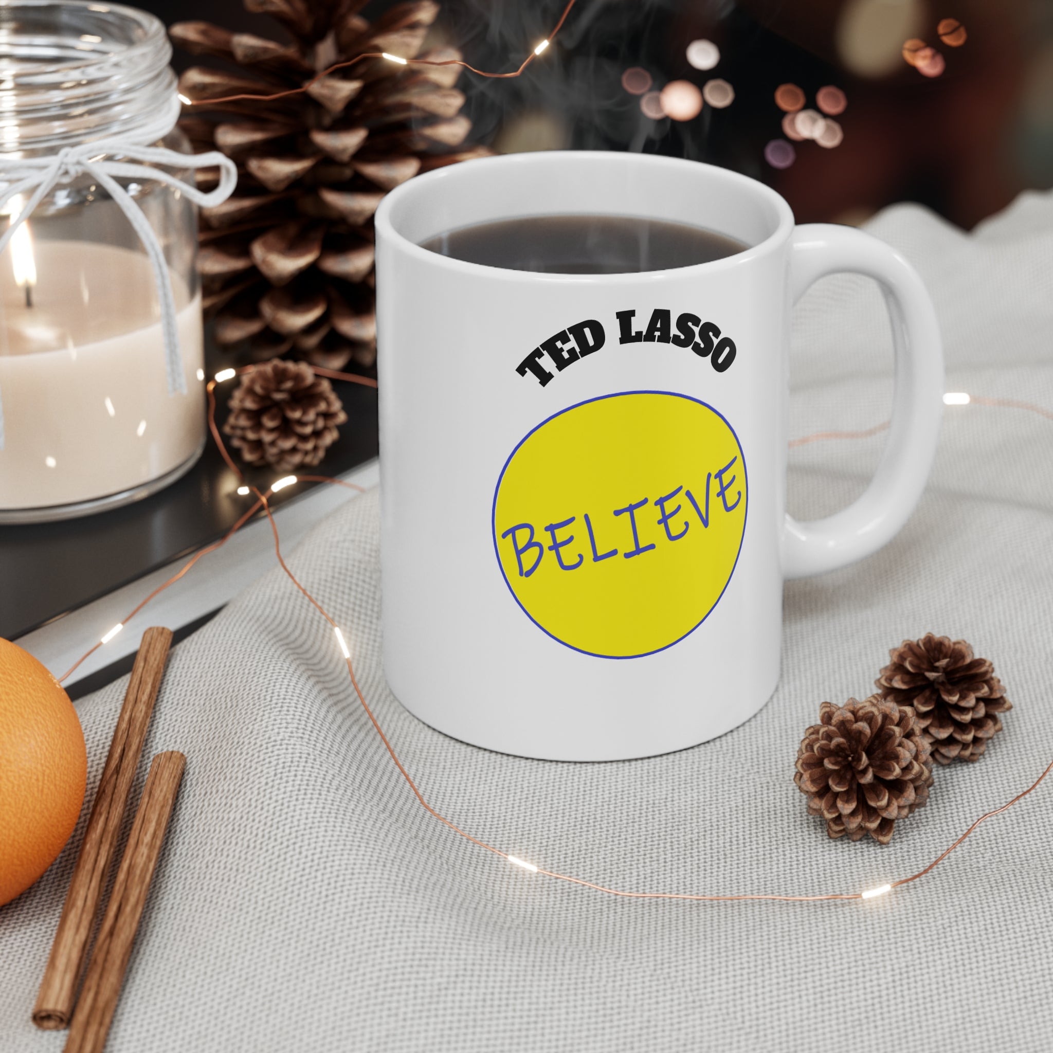 White mug with 'Ted Lasso Believe' design on a table with decorative items