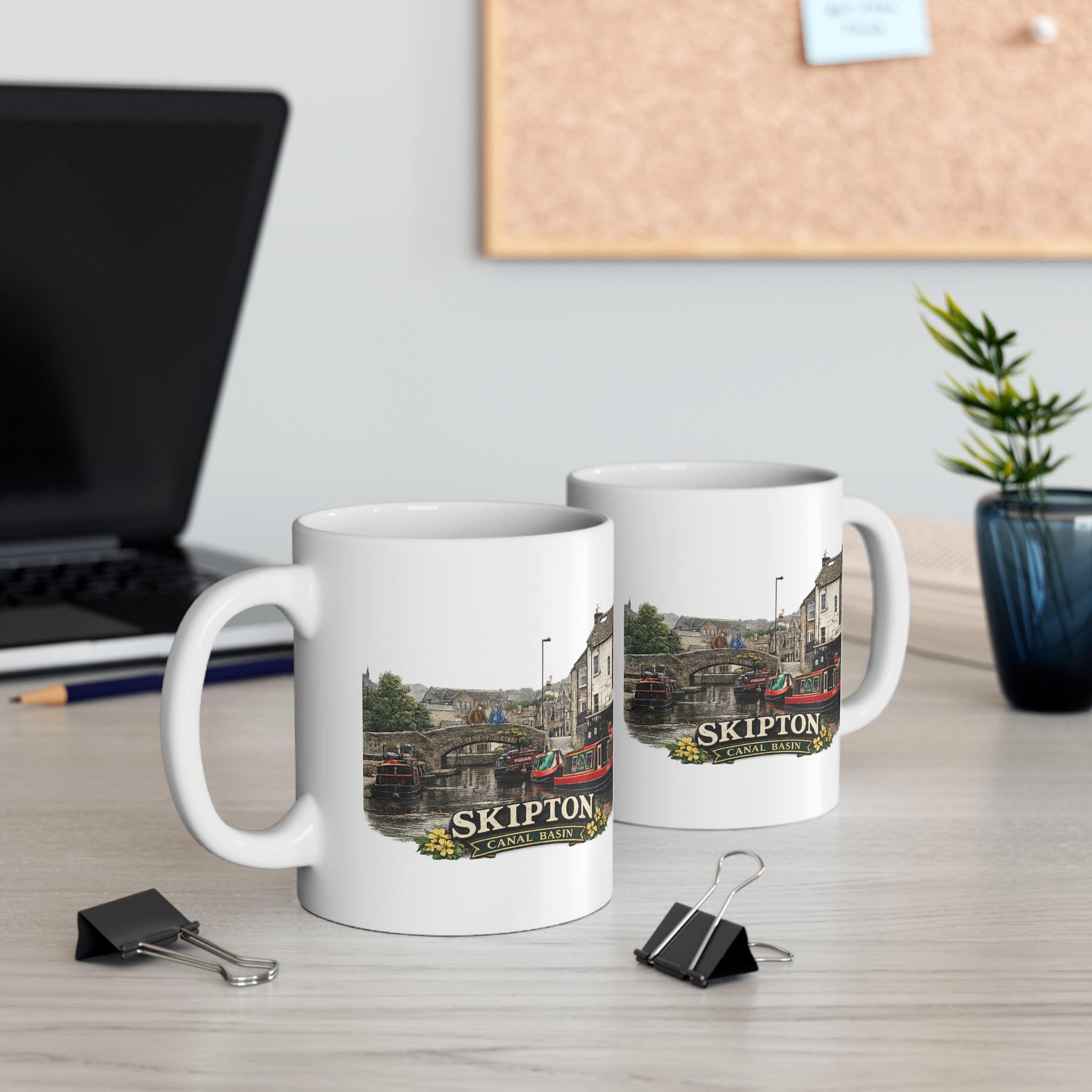 Two mugs with Skipton Canal Basin design on a desk with office items.