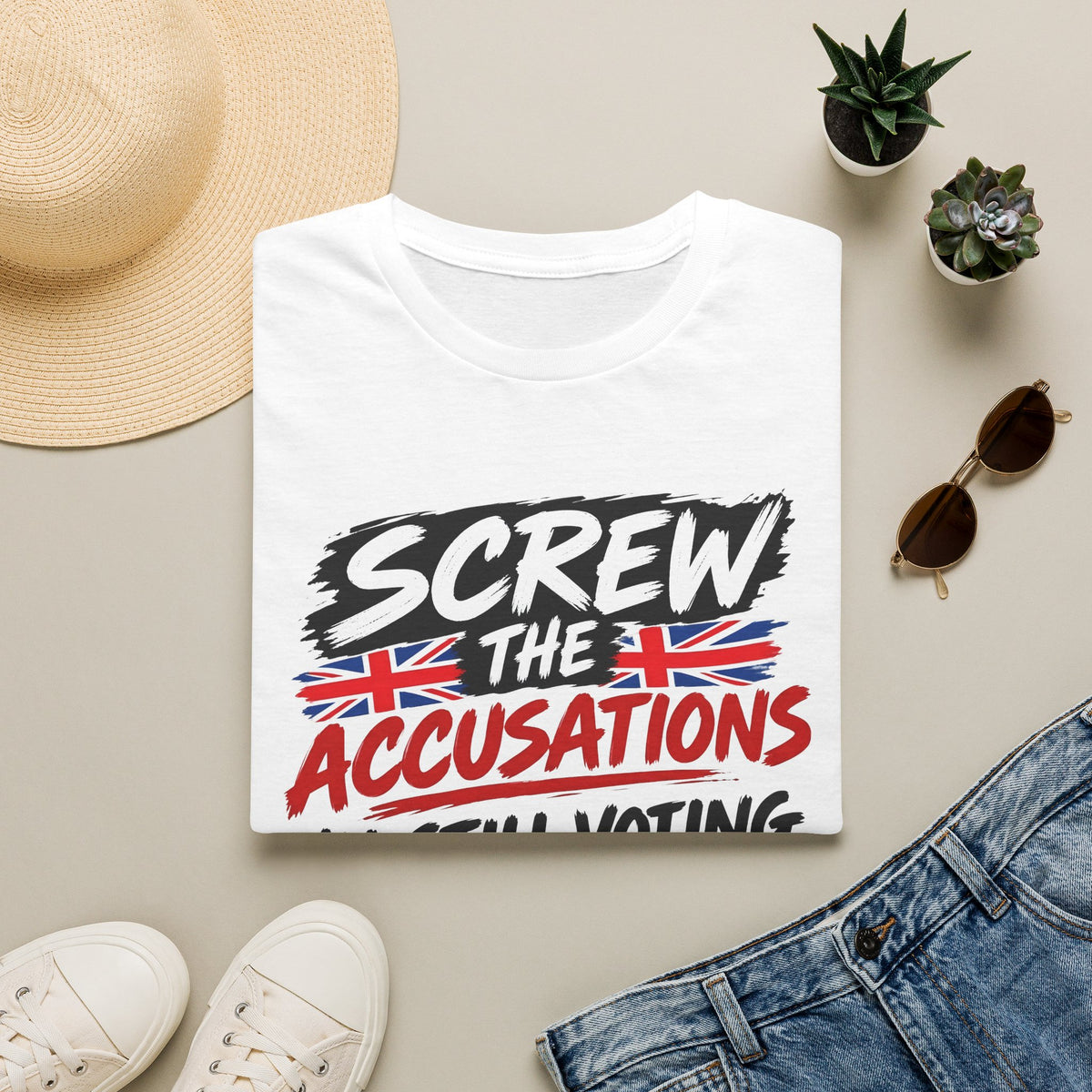 A folded white graphic T-shirt is displayed in a styled flat lay on a light beige surface. The shirt features the text 'SCREW THE ACCUSATIONS' with Union Jack flag graphics.