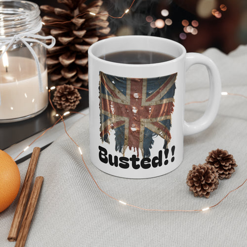 White mug with British flag design and 'Busted!' text, surrounded by decorative items on a table.