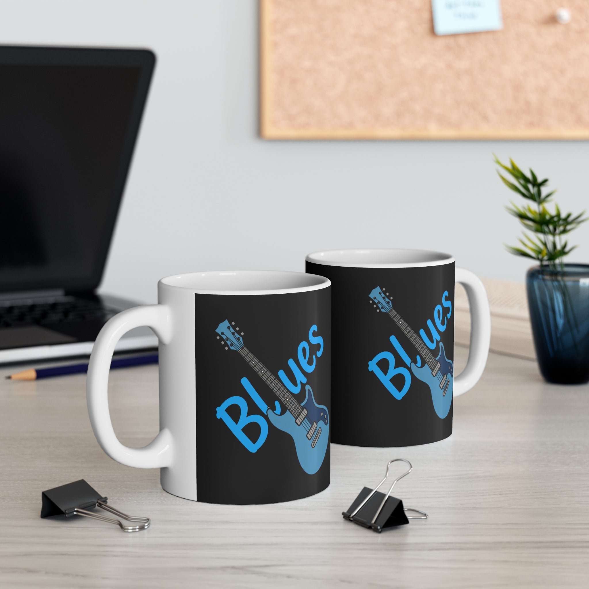 Two black mugs with 'Blues' and guitar design on a desk with office supplies.