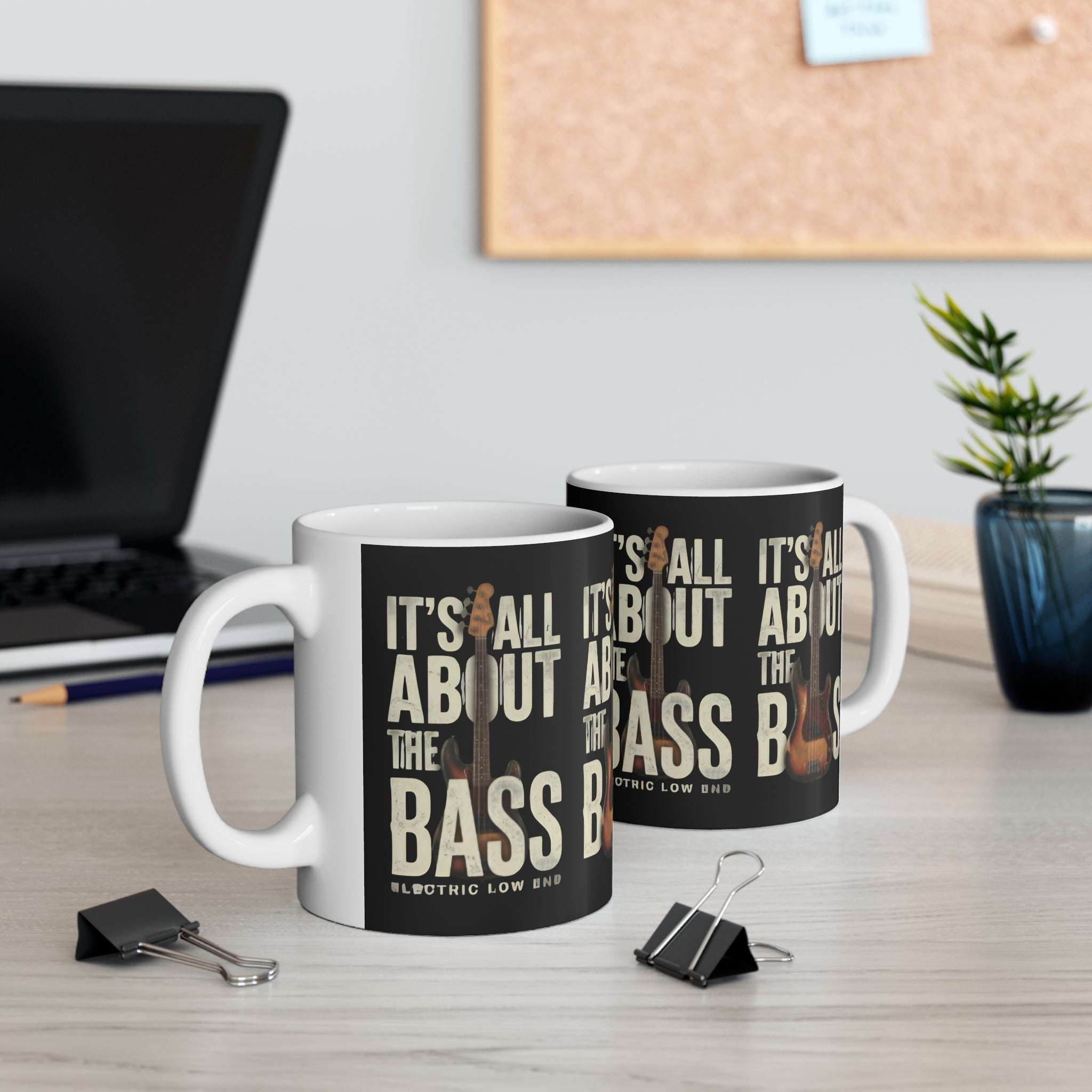 Two mugs with 'It's All About the Bass' text on a desk with office items.