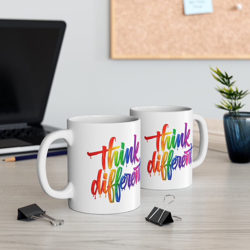 Two mugs with 'think different' text in colorful letters on a desk with office items.