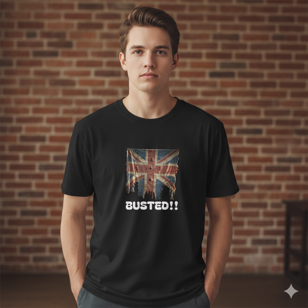 Person wearing a black t-shirt with a Union Jack design and 'BUSTED!!' text against a brick wall.