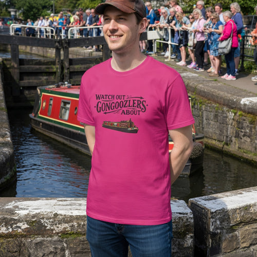 Man wearing a pink t-shirt with a canal boat design and Gongoozlers  text, standing by a lock with people and boats in the background.
