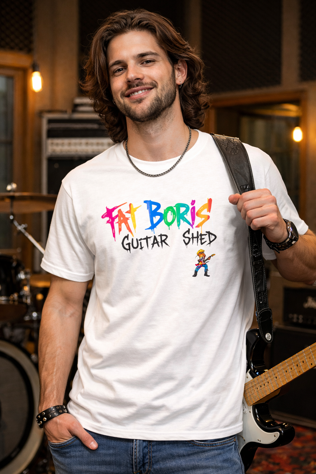 Man wearing a white t-shirt with 'Fat Boris Guitar Shed' design, holding a guitar in a music studio.