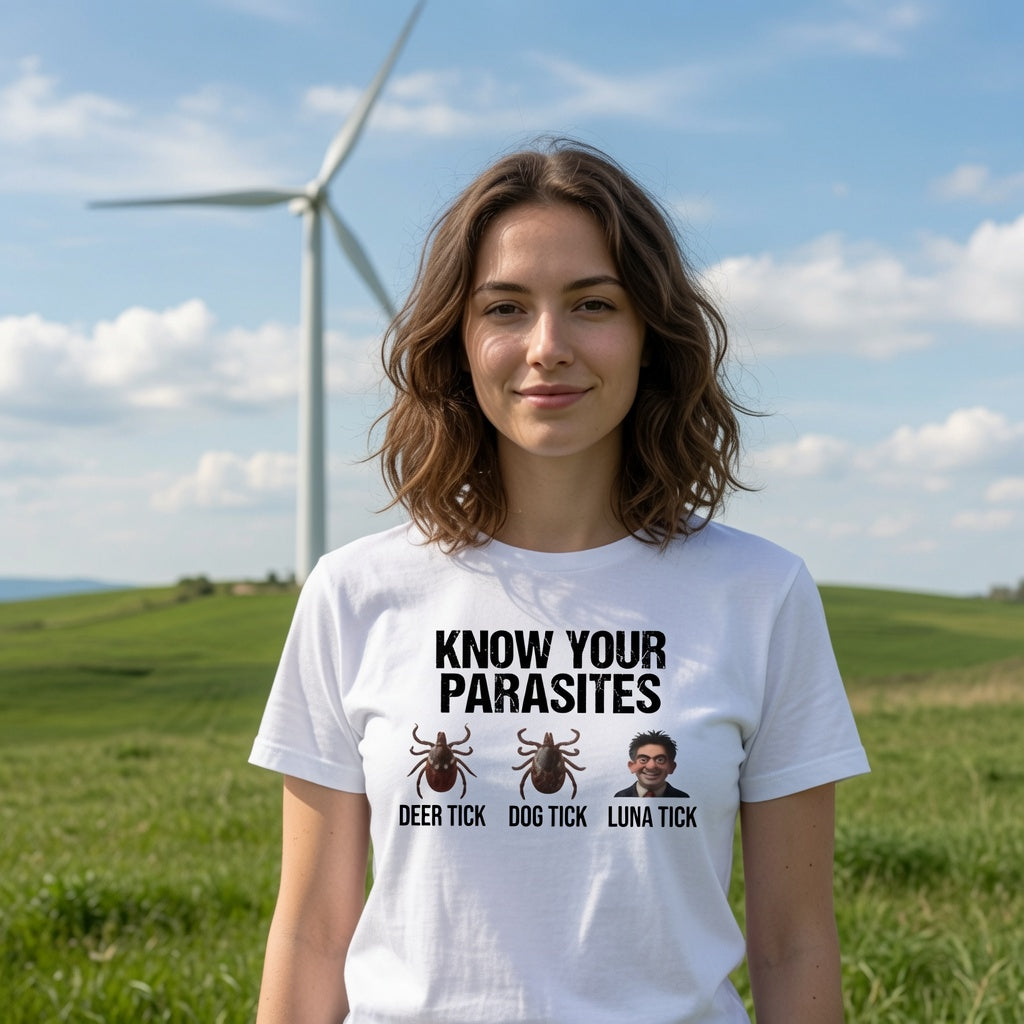A woman standing outdoors in a grassy field with a wind turbine and blue sky behind her, wearing a white graphic T-shirt with the text 'KNOW YOUR PARASITES' and three illustrated tick/bug graphics labeled 'DEER TICK', 'DOG TICK', and 'LUNA TICK'.