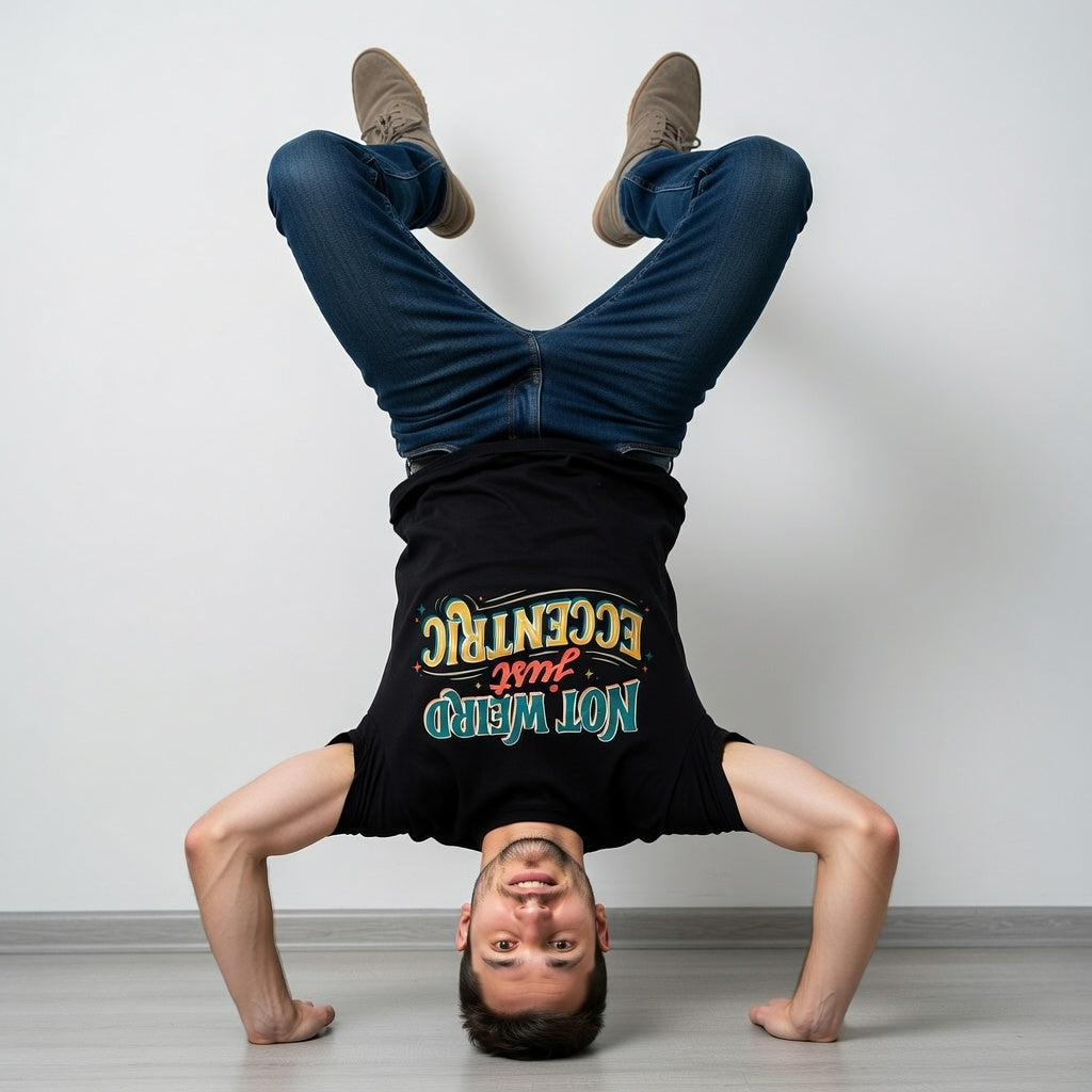 Person doing a handstand wearing a black t-shirt with colourful text not weird just eccentric on a plain background
