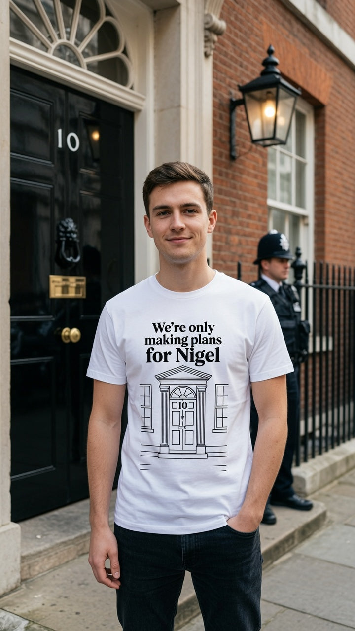 A man wearing a white graphic t-shirt with a black print of 10 downing street home door and the text 'We're only making plans for Nigel', standing in front of the black door of 10 Downing Street in London.